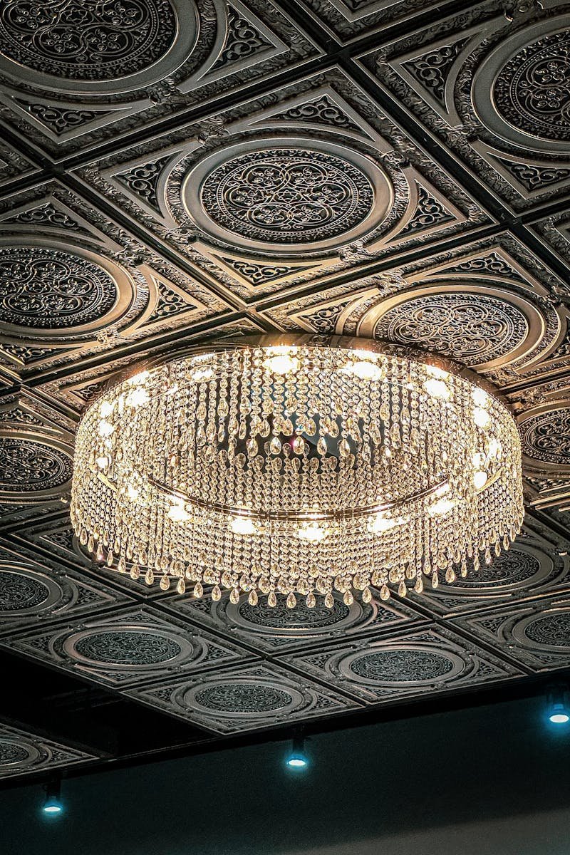 Luxurious crystal chandelier on an intricately designed ceiling, capturing elegance and style.