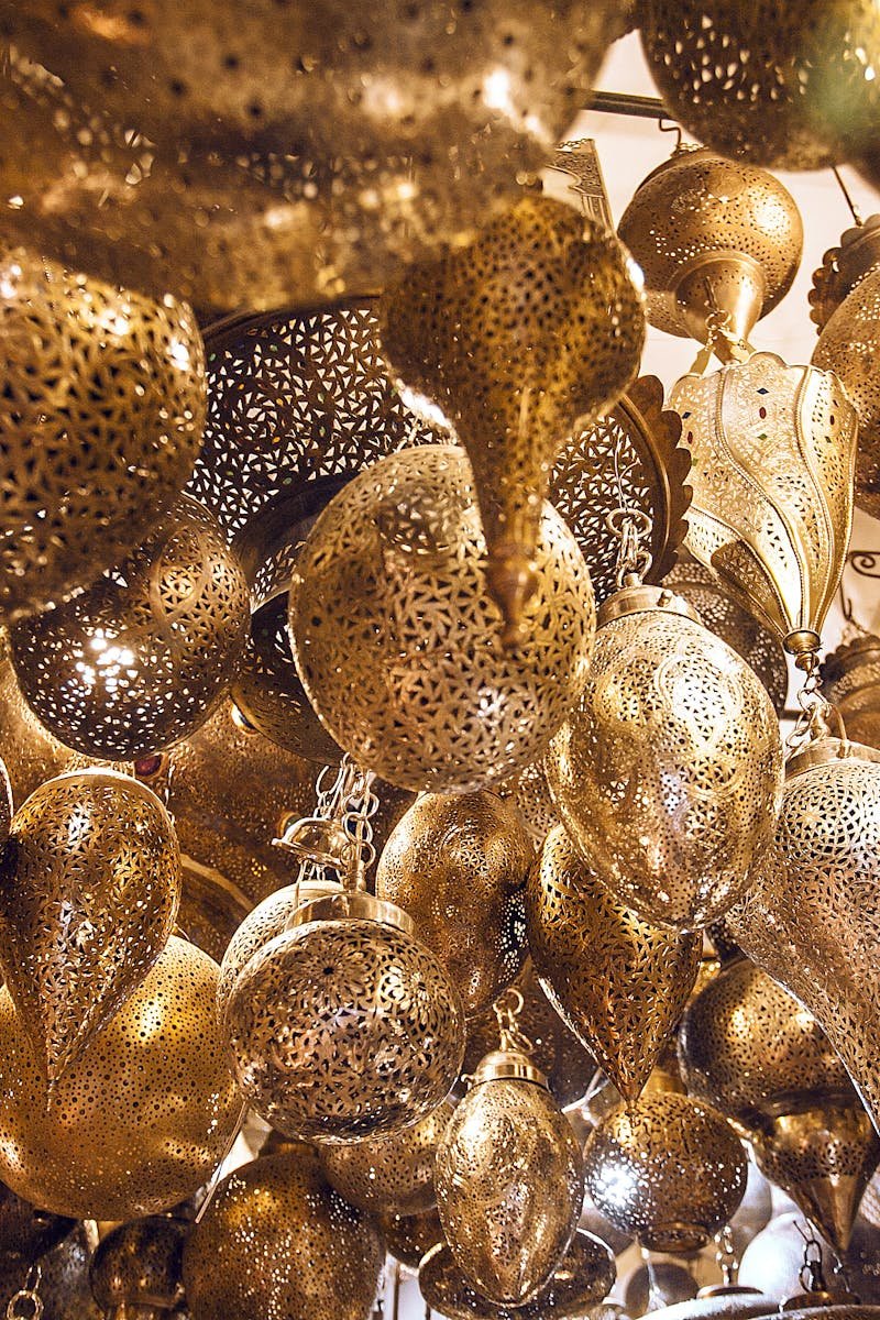 From below of assorted ornamental Moroccan lamps with tiny holes on shiny surface in local market